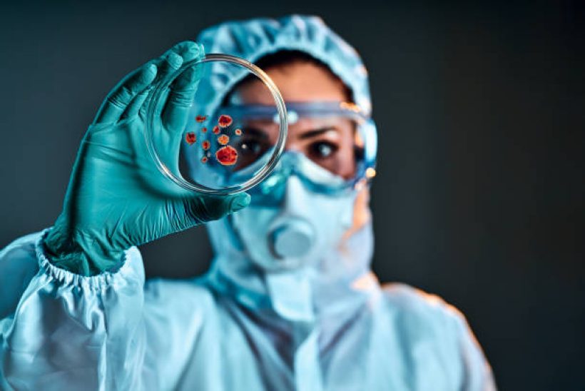 Selective focus of biochemist taking biomaterial from petri dish with tweezers.